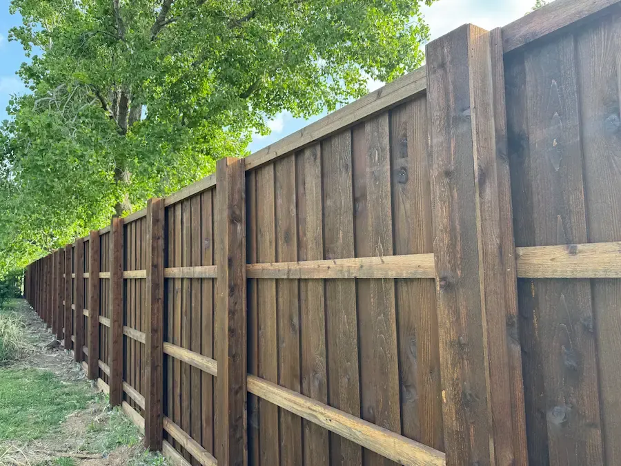 Board-on-board cedar fence seen from the rail side, with steel posts